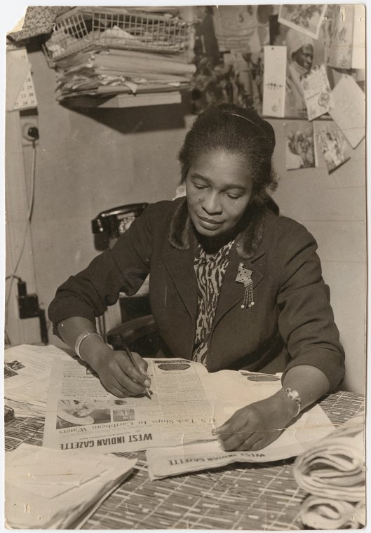 A woman seated and reading a newspaper