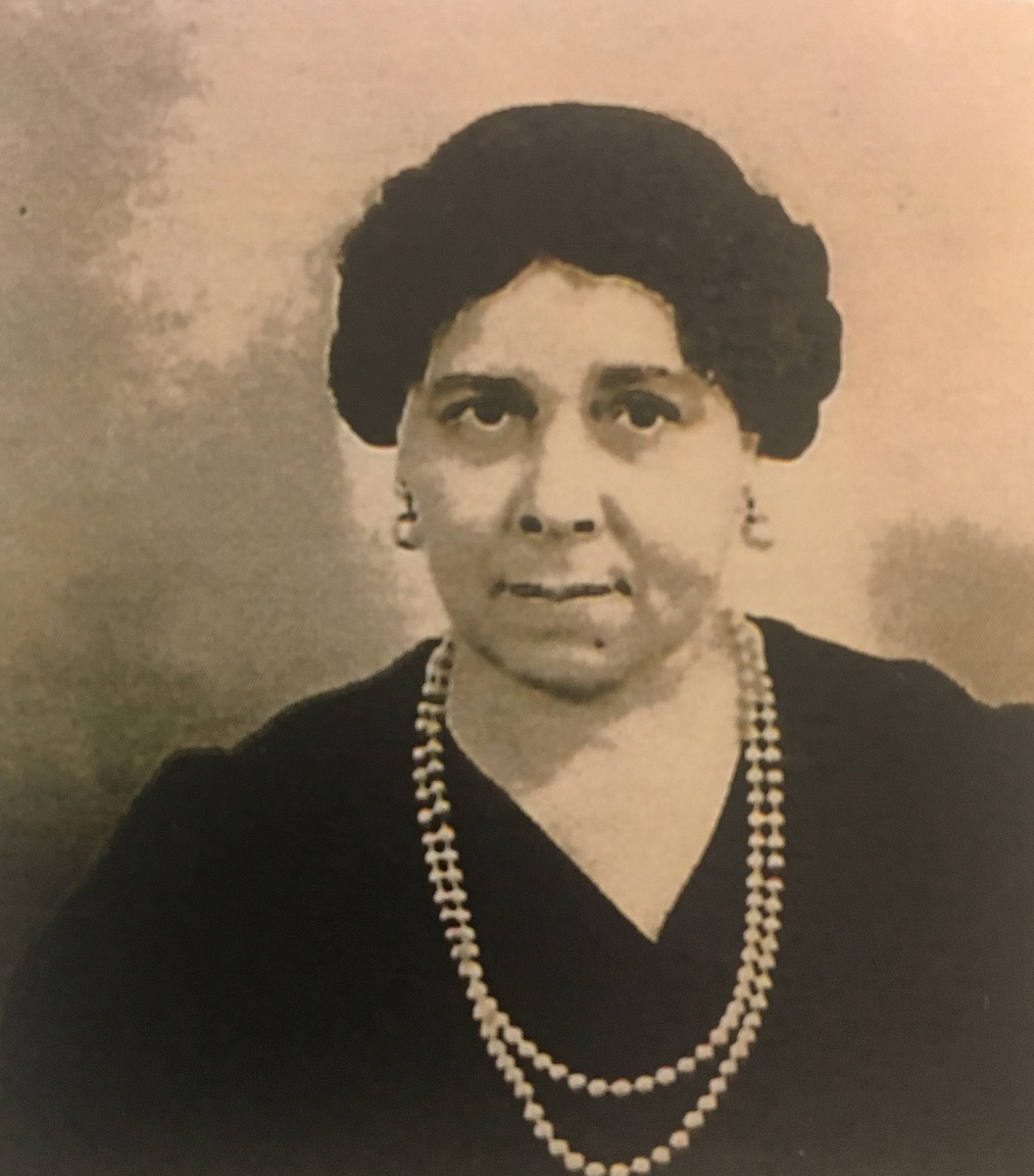 A woman facing forward wearing a pearl necklace