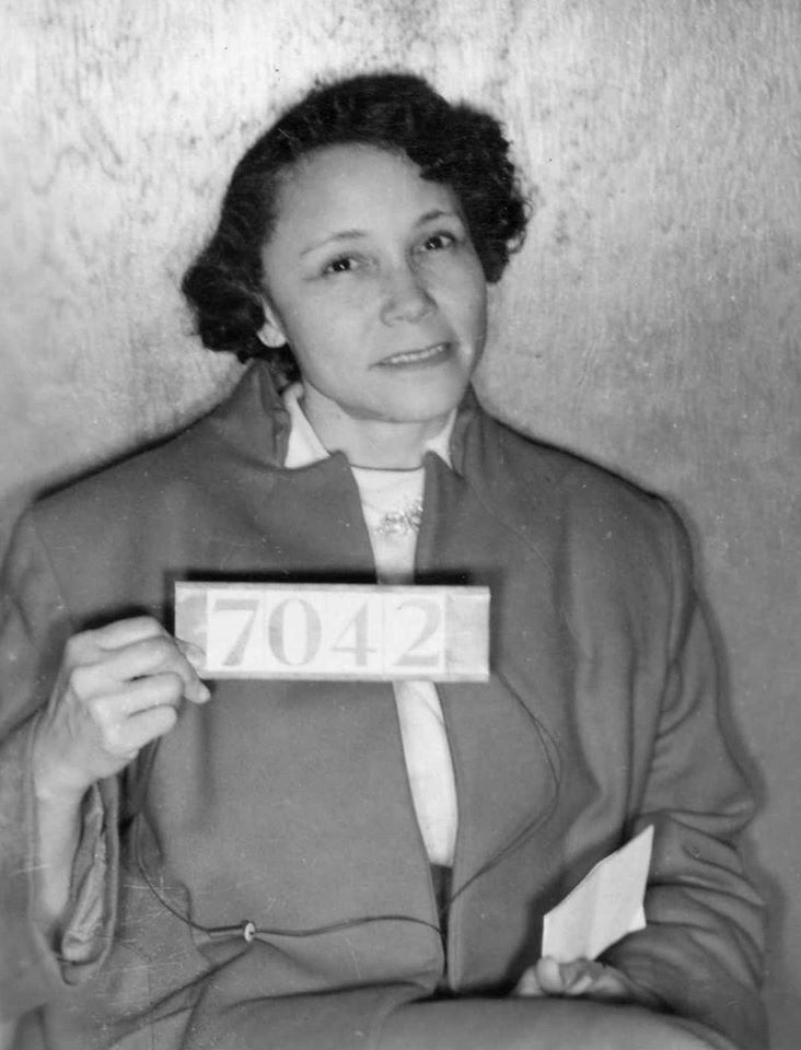 A woman seated and holding a sign with numbers