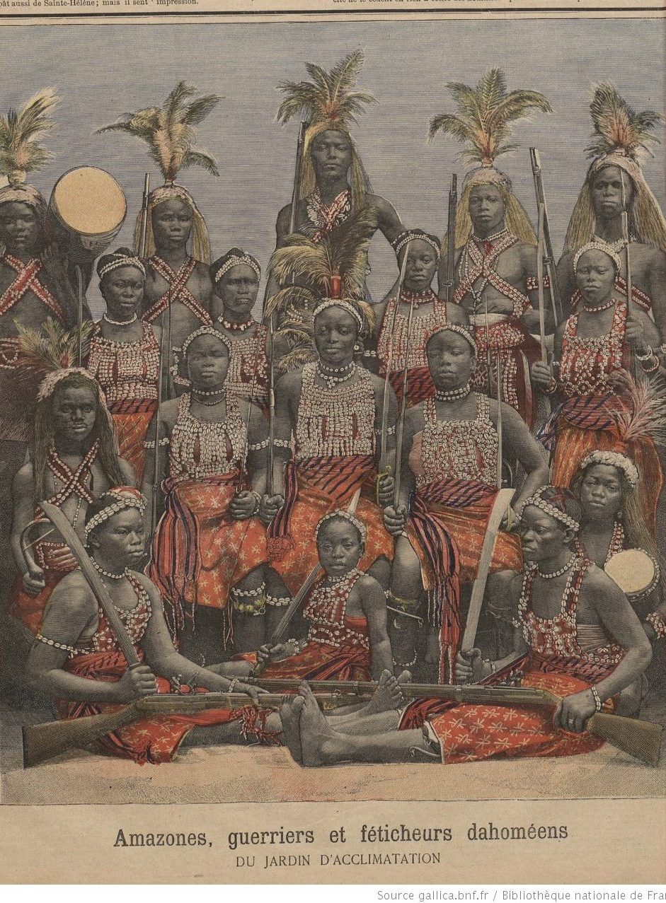 A newspaper/journal clipping showing men, women, and children dressed in colorful clothing and posed for a picture