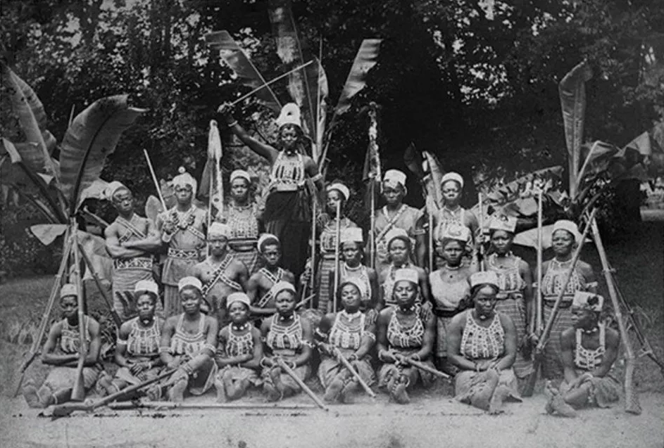 A group of people seated and posing with prop guns and swords