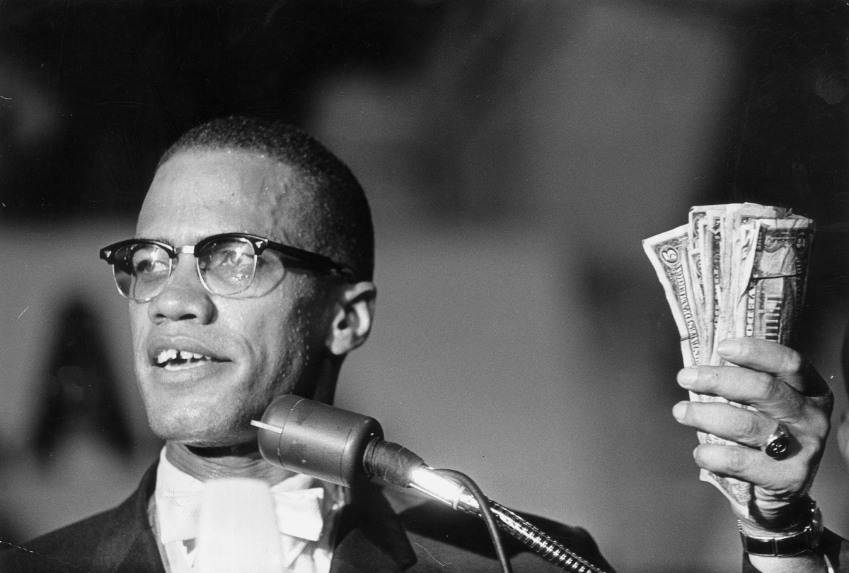 A man speaking into a microphone while holding cash in his hand